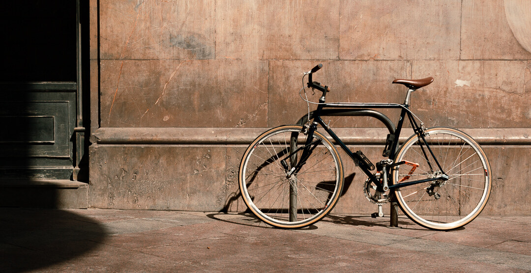A bicycle leaning against a sunlit stone wall in Alicante